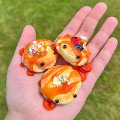 three little orange bears sitting on top of each other in the palm of someone's hand