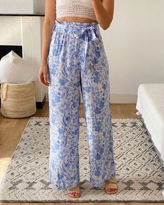 Our flowing Pants Blue Blossom are a flattering and elegant style, perfect for any season. Made from a lightweight and breathable fabric, they feature a full elastic waist and a detachable tie belt. With a beautiful blue flower print, these pants are a true statement piece. Pair them with our Breezy Blouse, Lace Bralette Lovebird and a tan slide for your daily grocery stroll or style with our Blouse Coco, fine jewels and a slim heel for an evening soiree. A touch of timeless elegance to your war Garden Party Wedding Guest, Floral Pants Outfit, Flowing Pants, Floral Palazzo Pants, Blue Blossom, Blue Flower Print, Resort Chic, Blouse Lace, Vacation Wardrobe