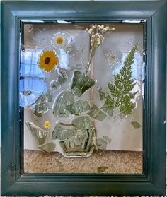 a glass frame with flowers and plants in it