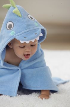 a baby laying on the floor wrapped in a blue towel