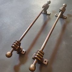 two metal handles with wooden knobs on top of a black table next to each other