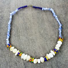 Solace Pearl Anang invites you to rejoice in the beauty of this eco-friendly necklace from Ghana. Circling the neck with blue agate beads this necklace is centered by a strand of colorful recycled glass that alternates with off-white agate stones. Petite beads of blue recycled glass flank the brass clasp. Unique Adjustable Beaded Necklace With Recycled Glass, Adjustable Beaded Recycled Glass Necklace, Ghana Beads Necklaces, Blue Beaded Necklace In Recycled Glass, Eco Friendly Necklace, Handcrafted Beaded Jewelry, African Glass Bead Necklace, Recycled Glass Bead, White Agate