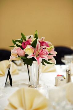 a vase filled with pink and white flowers on top of a table covered in napkins