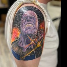 a man with a tattoo on his arm has an image of thanos in the background