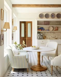 a dining room table with chairs and plates on the shelves above it, in front of a doorway