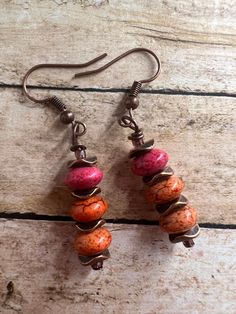 Earrings are on a copper wire with copper spacers, in between a peachy orange color bead. Bohemian Orange Copper Earrings, Orange Copper Bohemian Earrings, Handmade Orange Copper Earrings, Copper Jewelry With Dangling Beads, Red Copper Earrings, Handmade Pink Copper Earrings, Bronze Copper Earrings With Round Beads, Bronze Round Bead Copper Earrings, Orange Copper Earrings For Gift