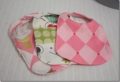 three baby bibs laying on top of each other in pink and white checkered fabric