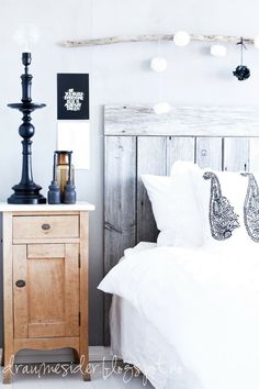 a bed with white sheets and pillows next to a wooden night stand in a bedroom