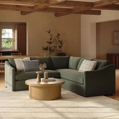 a living room with a sectional couch and coffee table in the center, surrounded by wooden beams