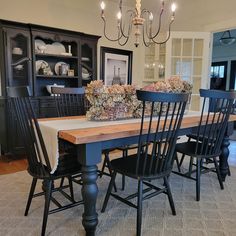 a dining room table with black chairs and a chandelier hanging from the ceiling