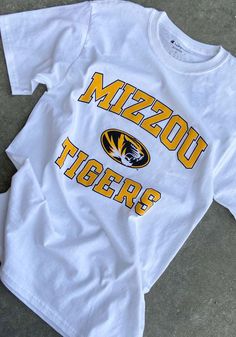 Champion Missouri Tigers White Arch Mascot Short Sleeve T Shirt - 14751951 White Game Day Fan Apparel T-shirt, White Fan Apparel T-shirt For Game Day, Varsity Logo Print T-shirt For Game Day, Collegiate Cotton T-shirt For Sports Events, Cotton T-shirt With Logo Print For Football Season, White Fan Apparel Tops For Fan Merchandise, White Fan Apparel Tops, White Fan Apparel Tops For Merchandise, White Fan Merchandise Tops