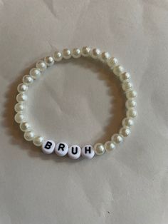 "\"BRUH\" - White artificial pearl bead, stretchy bracelet with acrylic letters * Hand-made using artificial pearl beads, 4x7mm white round acrylic alphabet beads and 0.8mm elastic string * Beautifully packaged in a sheer white drawstring organza bag" Beads Letters Bracelet, Round Beads Bracelet, Alphabet Beads Ideas, Bead Word Bracelet Ideas, Diy Pearl Bracelet Ideas, Bead Bracelet Ideas Words, Letter Bracelet Beads Ideas Funny, Letter Beads Ideas, Crystal Bead Bracelet Ideas