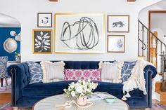 a living room with blue couches and pictures on the wall above them in various frames