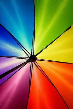 an open rainbow colored umbrella with the sun shining down on it's top half