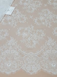 "Off white lace fabric. Both sides are scalloped. Width: 154 cm/60.6 inches Item number: LK3004 Made in Europe www.LaceToLove.com Price is set for one meter/yard. You will receive the fabric in one continuous piece if you purchase more than 1 meter/yard. IMPORTANT! Maximum one piece length of this lace is 3 meters/yards. If you buy more than 3 meters/yards of this lace you will receive it in several pieces. Actual color may vary greatly form the color you see on screen. It depends on your device Beige Lace Dress With Lace Trim, Elegant White Lace With Patchwork, Beige Scalloped Lace Dress, Cream Lace Dress With Delicate Details, Cream Lace Dress With Lace Trim For Ceremony, Cream Lace Dress With Lace Patchwork, Elegant White Scalloped Lace, Delicate White Lace With Lace Trim, Elegant Lace Trim Fabric