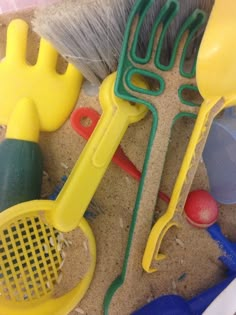 several different types of plastic toys on the sand, including rakes and shovels