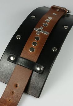 3" wide leather cuff made to resemble the same cuff worn by fictional character Merle Dixon. - The cross is 1" long. - Solid brass buckle closure. - Brass rivets, nickel and chrome polish. Edgy Leather Cuff Bracelet, Leather Punk Cuff Bracelet With Wrist Strap, Adjustable Leather Punk Cuff Bracelet, Punk Leather Cuff Bracelet With Wrist Strap, Punk Leather Cuff Wristband, Leather Cuff Bracelet With Rivets, Adjustable Leather Gothic Wristband, Adjustable Gothic Leather Wristband, Merle Dixon