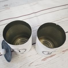 two empty cups sitting on top of a white wooden table next to a can opener