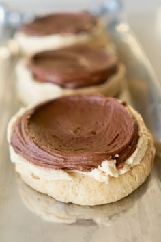 three cookies with chocolate frosting on them sitting on a counter top next to each other