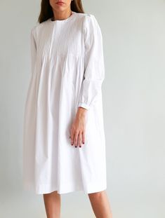 "✨ DETAILS White oversized midi dress with top pleated bodice detail. Featuring a round neckline and long sleeves. Back buttons. Mid calf length. Lightweight fabric. Handmade in Bali: 100% Cotton ✨ CARE INSTRUCTIONS Hand wash in cool water or gentle wash machine - Air Dry ✨ SIZE Model measurements (wearing size S) Height - 1.72 m / 5' 8\" Bust - 86 cm / 34 in Waist - 63 cm / 25 in Hips - 91 cm / 36 in ✨ SHIPPING Please leave a note with a phone number when making a purchase since it might be nee