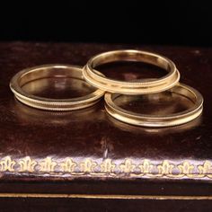 three gold wedding rings sitting on top of an old book