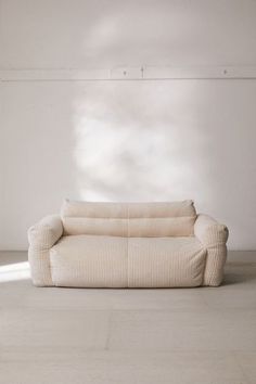 a couch sitting on top of a hard wood floor next to a white brick wall