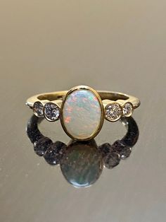 an opal and diamond ring sitting on top of a table