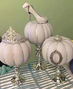 three white pumpkins sitting on top of a table next to each other with high heel shoes