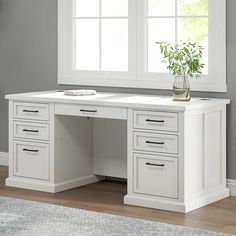 a white desk with drawers and a potted plant