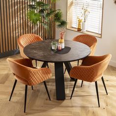 a table with four chairs around it and a potted plant in the corner on top