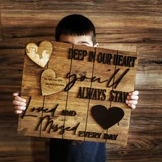 a young boy holding up a wooden sign that says deep in our heart, don't always stay and miss every