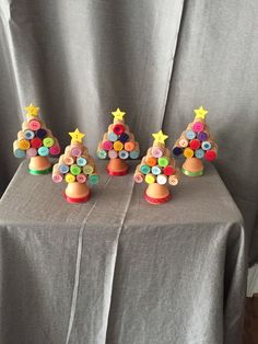 small christmas trees made out of buttons on top of a gray tablecloth with a curtain in the background