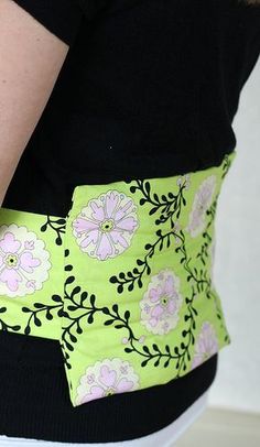 a woman wearing a green and pink belt with flowers on the waist, holding her hand in her pocket