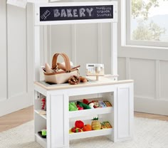 a small white table with a basket on top of it next to a sign that says bakery