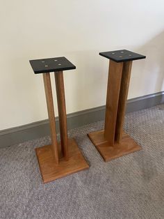 two wooden pedestals with black tops on carpeted floor