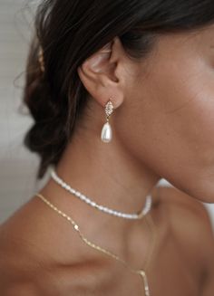 a close up of a person wearing a necklace and earring with pearls on it