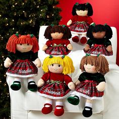 a group of dolls sitting on top of a white couch next to a christmas tree