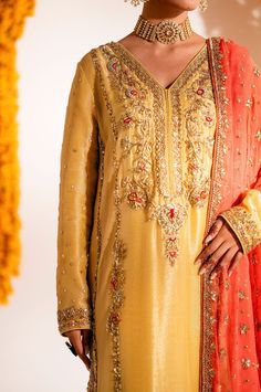 Yellow Mehndi Dress in Kameez Trouser Dupatta Style is a traditional masterpiece that will give you a head-turning flawless look on the big day. Hand-crafted details of tilla, dabka, sequins, and gota make this stunning Pakistani Dress an epitome of beauty and your foremost priority. Yellow Kameez: The kameez in an alluring yellow color is beautifully embellished with zardosi, tilla, dabka, and Resham. The stunning details of gota give a traditional touch to this beautiful kameez. Embellished neckline and borders make this kameez a perfect choice to wear on Mehndi. Kameez Trouser: The Embellished yellow kameez is paired with trousers, creating a lavish Pakistani Mehndi Dress. The borders of these trousers are hand-embellished, giving a heritage traditional touch to this overall attire in p Transitional Reception Kurta With Dupatta, Kurta With Dupatta For Reception And Transitional Events, Traditional Chanderi Kurta For Reception, Silk Churidar For Eid Reception, Silk Churidar For Reception During Eid, Silk Unstitched Suit For Reception And Navratri, Anarkali Churidar For Wedding Transitional Season, Anarkali Churidar For Wedding During Transitional Season, Raw Silk Churidar With Resham Embroidery For Reception