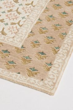 a beige rug with blue and gold designs on it's edges is laying on a white surface