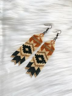 two pairs of beaded earrings with black and brown beads on white furnishing