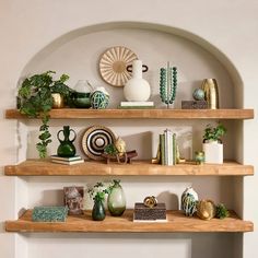 three wooden shelves with plants and vases on them