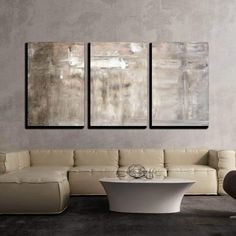 three abstract paintings hang on the wall above a white couch in a modern living room