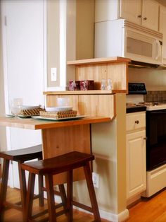 a kitchen with an oven, microwave and small table in the corner next to it