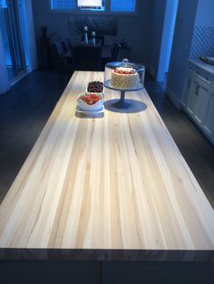 two cakes sitting on top of a wooden table in a kitchen next to a window