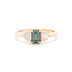 a gold ring with an emerald and three baguettes on the side, set in yellow gold