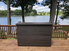 a large brown box sitting on top of a wooden deck next to a body of water