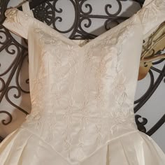 the back of a wedding dress hanging on a wrought iron rack in front of a mirror