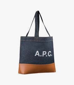 - Tote bag in Japanese canvas. - Two large handles to carry the bag by hand or on the shoulder. - Large panel in smooth leather at bottom of bag. - Reinforced base. - Interior zip pocket. - Large A.P.C. logo in front. - Caramel topstitching on the denim. Faux Leather Bag, Exclusive Clothing, C Logo, Backpack Tote Bag, Katie Holmes, Scarf Jewelry, Tote Backpack, Weekender Bag, Cloth Bags