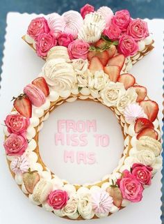 a cake decorated with strawberries and flowers on top of a white plate that says from his to mrs