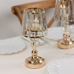 two clear glass candlesticks sitting on top of a white table